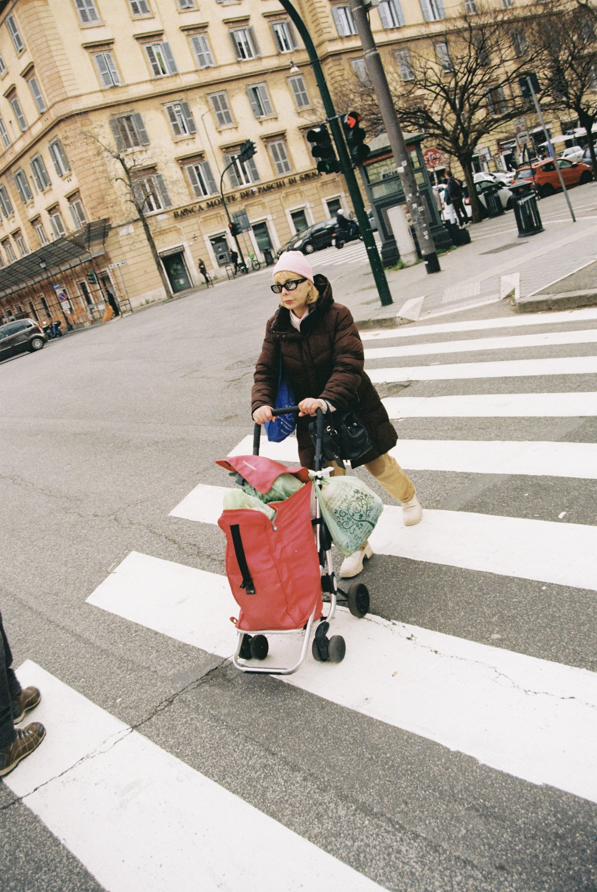 photo of woman pushing shopping basket across the road